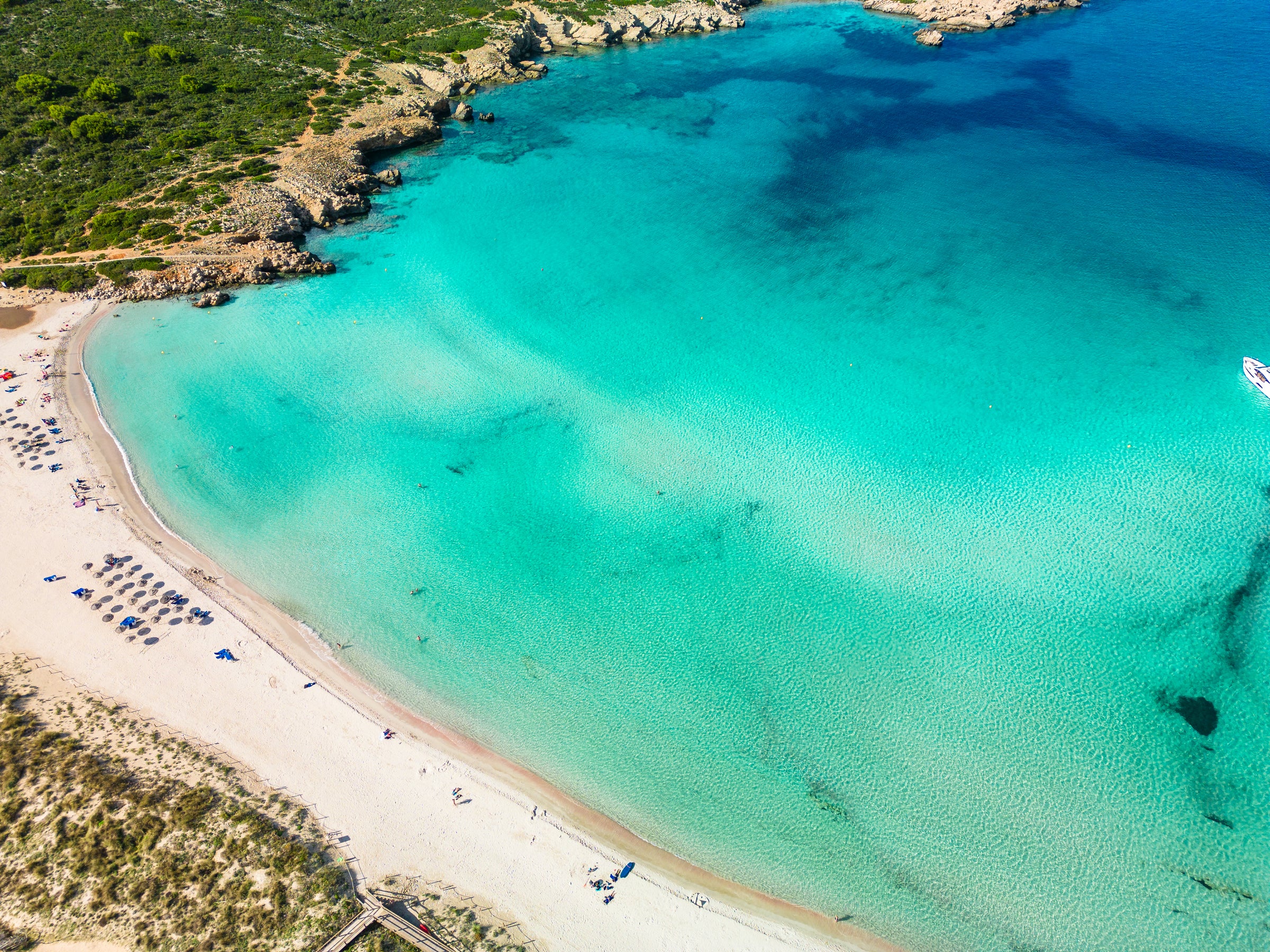 Aerial view of a beach with clear turquoise water and sandy shore.