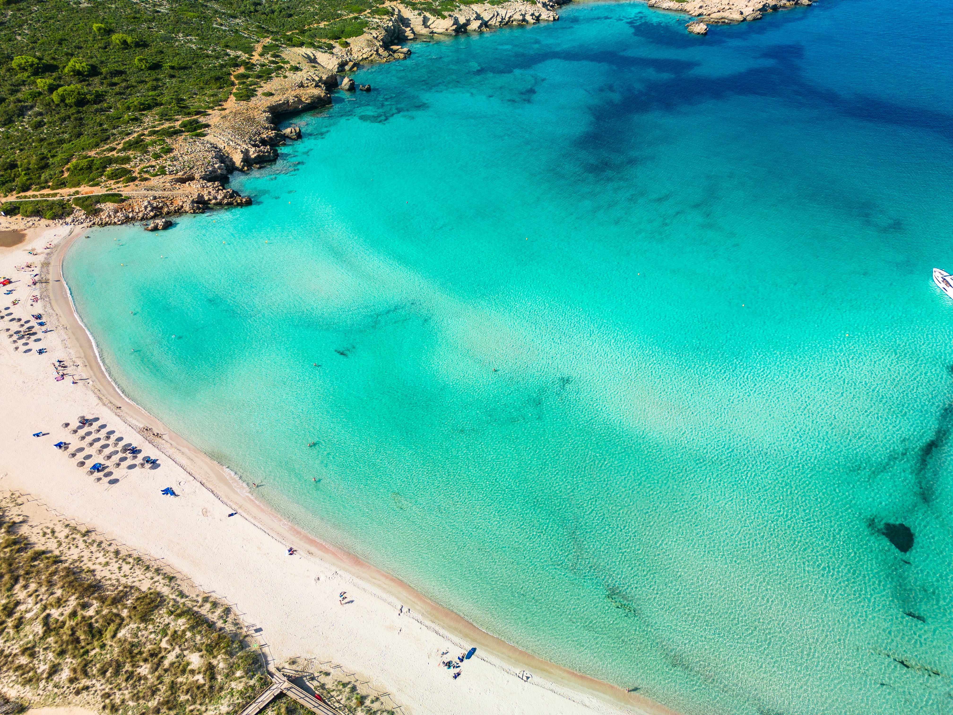 Aerial view of a beach with clear turquoise water and sandy shore.